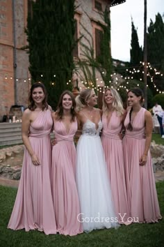 four bridesmaids in pink dresses posing for a photo at their wedding reception outside