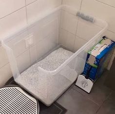 a trash can sitting on the floor next to a drain in a tiled bathroom stall