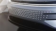 the front grille of a car with white dots on it's grill and hood