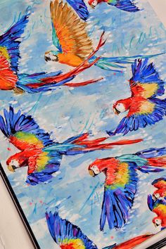 colorful parrots are flying in the sky on blue watercolor paper with white background