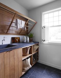 a kitchen with wooden cabinets and blue counter tops next to a white sink in front of a window