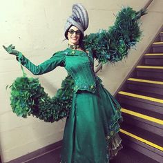 a woman dressed in green is standing on the stairs