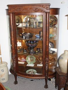 an old china cabinet with glass doors and wooden carvings on the front, along with other antique items