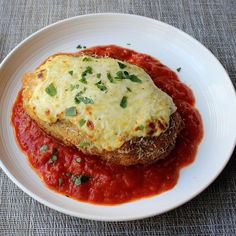 a white plate topped with an eggplant covered in sauce