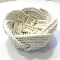 a white rope that has been knotted into a bowl on top of a table and is ready to be used as a decoration