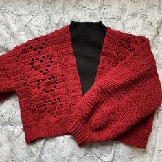 a red knitted sweater laying on top of a bed