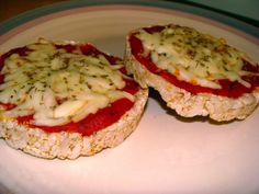 two pieces of food sitting on top of a white plate with sauces and cheese