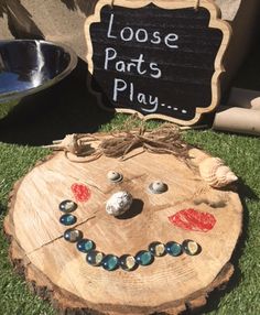 a close up of a piece of wood with buttons on it and a sign that says loose parts play