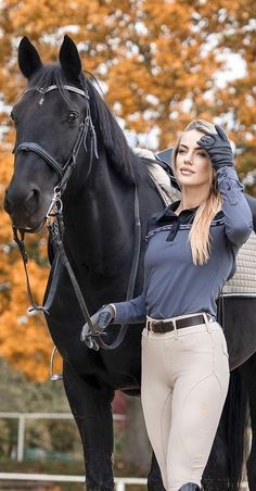 a woman is standing next to a black horse