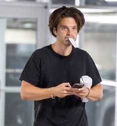 a man holding a cell phone in his mouth while standing next to an airport door