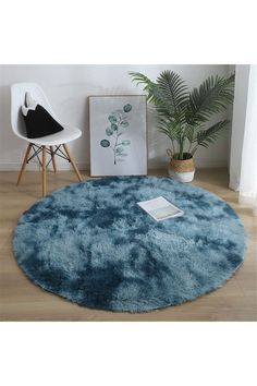 a blue round rug in the middle of a room with a chair and potted plant