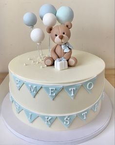 a teddy bear sitting on top of a cake with balloons in the shape of letters