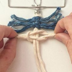 two hands are working on a piece of yarn