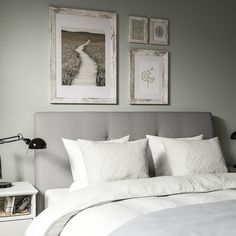 a bed with white linens and two framed pictures on the wall next to it