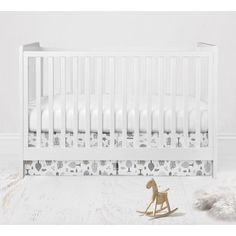 a white crib with a wooden rocking horse next to it and a sheep rug on the floor