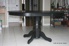 a black table sitting in the middle of a room with white tile flooring and an open door