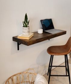 a laptop computer sitting on top of a wooden shelf next to a chair and table