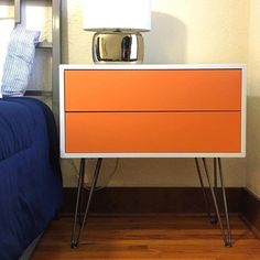 an orange and white dresser next to a bed with a blue comforter on it