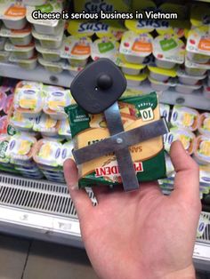 a hand holding a piece of food in front of a store shelf