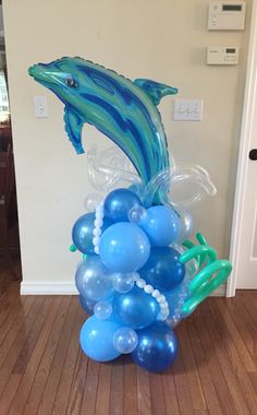 a dolphin balloon sculpture on the floor in front of a door with balloons attached to it