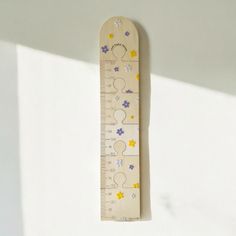 a wooden ruler with flowers on it hanging from the wall next to a white wall