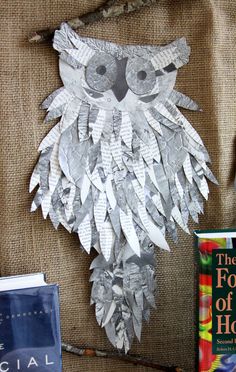 an owl made out of paper sitting on top of a table next to some books