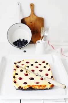 a white plate topped with a piece of cheese covered in berries