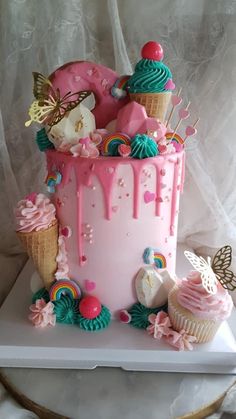 a pink cake with ice cream and cupcakes on it