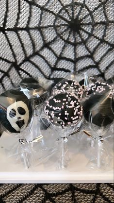 some black and white cake pops with sprinkles on them sitting in front of a spider web