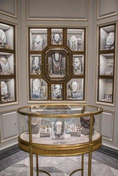 a display case filled with jewelry in front of several framed glass cases on the wall