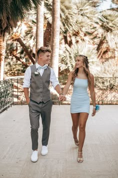 a man and woman walking down a walkway holding hands