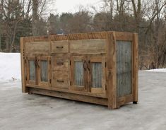 a wooden cabinet sitting on top of snow covered ground