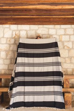 a black and white striped blanket sitting on top of a wooden bench next to a brick wall