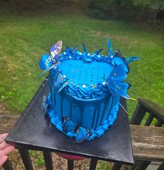 a blue cake sitting on top of a wooden table next to a green grass covered field