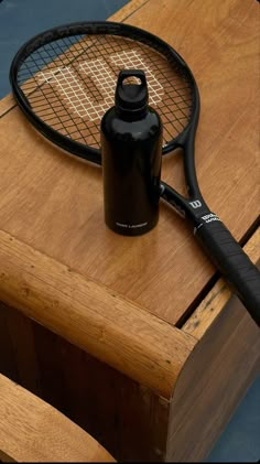 a tennis racket and water bottle sitting on top of a wooden table