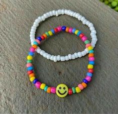 two bracelets with smiley faces on them sitting on top of a stone slab in the sun