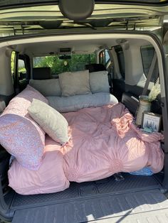 the back end of a van with pillows and blankets in the cargo area on it