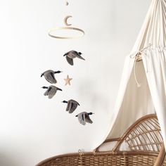 three birds are flying in the air near a hanging mobile with stars and crescents