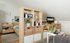 a living room filled with furniture next to a bed and a tv on top of a wooden shelf