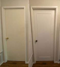 an empty room with two white doors and hard wood flooring