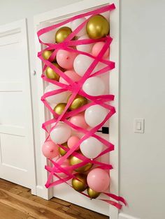 a door decorated with pink and gold balloons, streamers, and heart shaped balloons