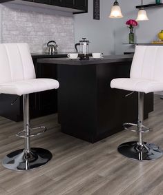 two white bar stools sitting in front of a counter