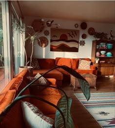 a living room filled with lots of furniture next to a large glass wall window covered in plants