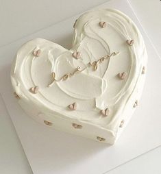 a heart shaped cake with white frosting and hearts on it