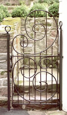 an iron gate is open on the side of a stone building