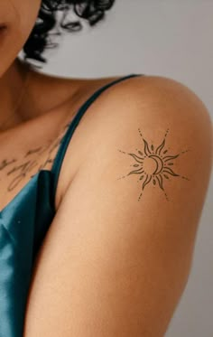 a woman with a sun tattoo on her left arm and shoulder is looking at the camera