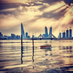 a boat floating on top of a body of water near a tall building under a cloudy sky