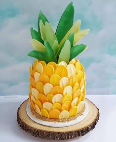 a pineapple cake with yellow and white frosting on a wood slice in front of a blue sky