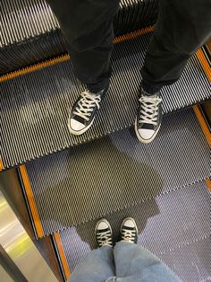 two people standing on an escalator with their feet up