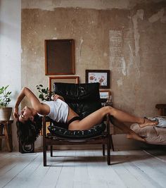 a woman laying on top of a chair in a room